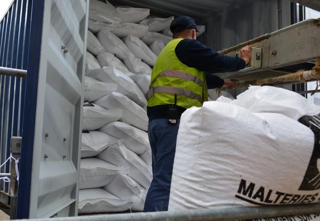 Un chauffeur range les sacs dans la remorque du camion